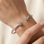 Silver bangle with Koala designs on a wrist against a neutral background