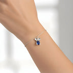 Silver bracelet with a Koala sapphire heart shape charm on a person's wrist against a white background
